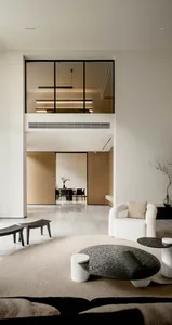 A modern minimalist living room with white furniture, black tables, and a concrete floor.
