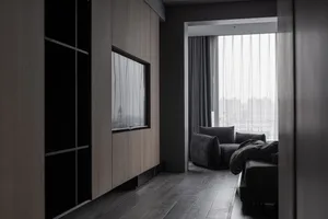 Modern living room with dark wood flooring, dark curtains, and a dark sofa with pillows.