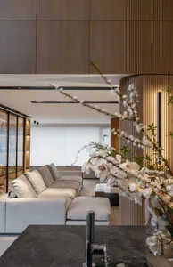 Modern living room featuring a white sectional sofa, wooden paneling, and glass windows.