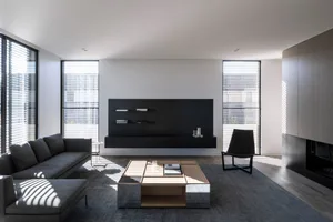 A modern living room with a black entertainment center, gray sectional sofa, and a wooden coffee table.