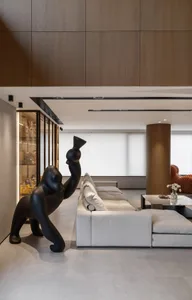 Modern living room featuring a large white sofa, a black sculpture, and wooden paneling on the walls and ceiling.