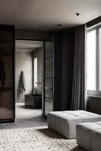 A modern, minimalist bathroom with industrial elements featuring concrete walls and floor, a glass shower enclosure, and a si