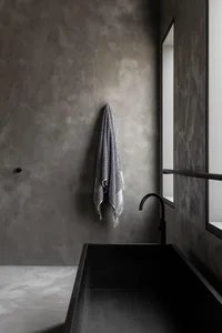 Modern minimalist bathroom with concrete walls and a black freestanding tub.