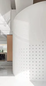 Modern interior architecture featuring a sleek, white, matte metallic wall panel with perforated holes.