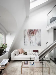 A modern living room with a white sofa, abstract art piece, and minimalist decor.