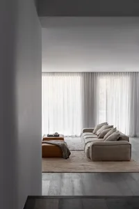 A modern living room featuring a fabric couch and leather ottoman.