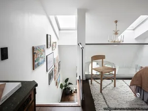 Modern minimalist bedroom featuring a carpeted floor, wooden chair, and skylights.