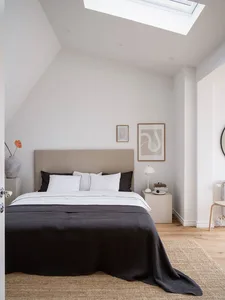 Minimalist bedroom with a bed, white walls, and a skylight window.