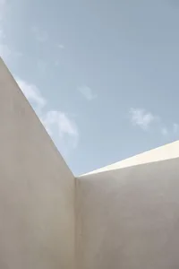 A minimalist concrete texture against a blue sky with light clouds.