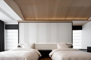 A modern bedroom with two beds, white linens, and a wooden headboard, under a wooden ceiling.
