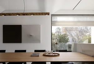 Modern conference room with a wooden table, black chairs, and minimalist decor. Large window with city view.