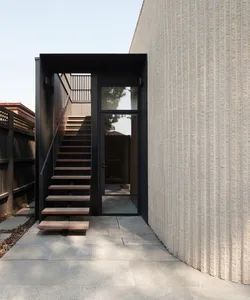 Modern entrance featuring wooden stairs and a concrete wall