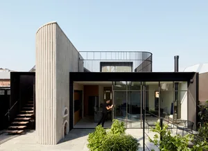 A modern home featuring a unique curved wall made of beige concrete.