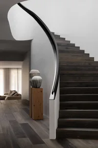 Modern house with wooden stairs and a curved black railing.