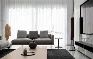 A modern minimalist living room with grey sofa, wooden coffee table, and glass elements