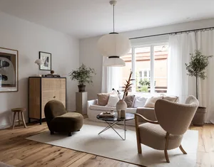 A modern living room with neutral tones and minimalist decor, featuring a white sofa, beige armchair, and wooden floor.
