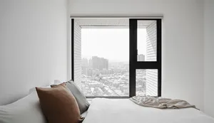 A minimalist bedroom featuring a bed with soft textiles, white brick texture walls, and white walls.