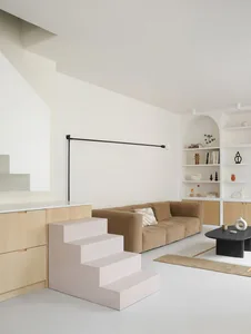 Minimalist living room featuring concrete steps leading to a seating area with a brown sofa and black coffee table, surrounde