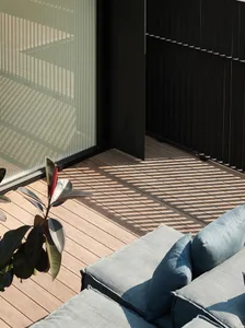 A modern patio featuring a wooden seating area with blue cushions and a plant.
