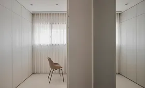 A minimalist wardrobe room with transparent curtains and neutral-color cabinets.