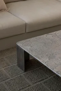 A modern interior setting featuring a silver coffee table with a textured surface.