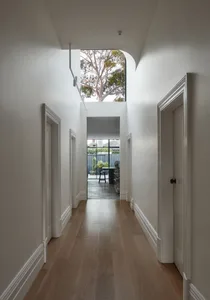Modern white interior design hallway with hardwood floors and natural light from skylight.