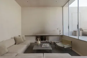 A minimalist living room with neutral-tones furniture and a fireplace.