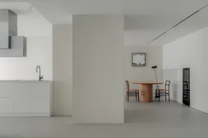 A minimalist kitchen with white cabinets and wooden flooring.