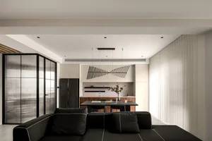 Modern, minimalist living room with black furniture, white walls, and a large window.