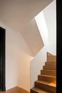 Modern staircase with wooden steps in a white interior space.