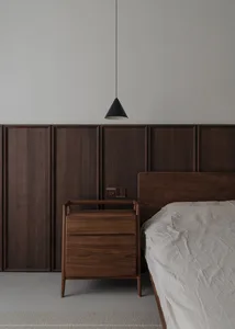 A minimalist bedroom featuring wooden furniture and a grey floor.