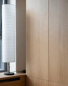 A minimalist interior featuring wooden cabinets and a cylindrical lamp.