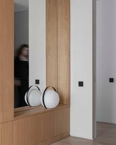 A modern, minimalist wall-mounted cabinet with a sleek, round light fixture mounted above it.