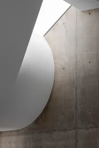 A minimalist modern staircase with concrete walls and ceiling, featuring clean lines and natural light.