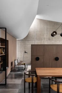 A minimalist industrial-style room with concrete and wood elements, featuring a wooden dining table and concrete wall.