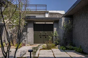 A minimalist residential exterior with concrete walls and a green wooden door.