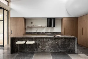 A modern kitchen with a marble island and wooden cabinets.