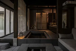 A sleek, minimalist interior with concrete walls and floor, featuring a small indoor water feature and a comfortable seating