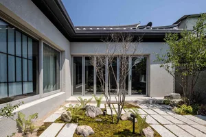Modern minimalist residential exterior featuring concrete, rock, and plant elements