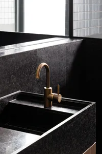 A modern, industrial-style bathroom featuring a black granite sink and faucet.