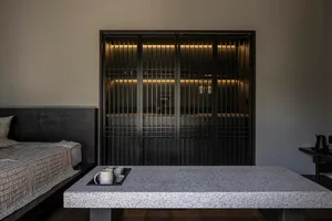 A minimalist bedroom featuring a granite table with a tray holding a small arrangement of coffee cups and mugs.