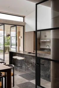 Modern kitchen interior with black and white marble countertops and stools.