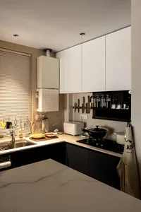 Modern kitchen with minimalist design featuring white cabinets, black countertops, and stainless steel appliances. Includes m