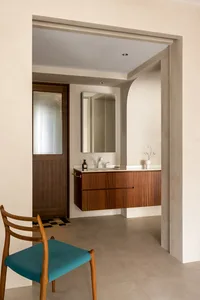 A minimalist bathroom with a wooden vanity, glass-front door, and soft, neutral color palette.