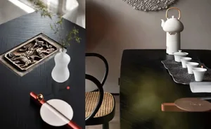 A sophisticated ceramic tea table setting with a white teapot and cups, a decorative plate, and a small vase with greenery.