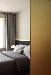 A minimalist bedroom with grey and white textiles and white pillows.
