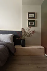 Minimalist bedroom featuring a wooden platform, white bedding, and floral arrangement.