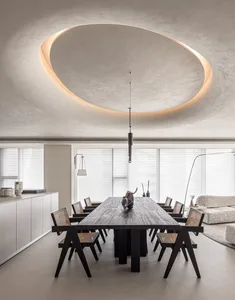 Modern dining room featuring a long wooden table with black legs and matching wooden chairs, set against a concrete ceiling w