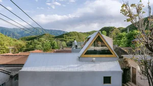 A modern house with a metallic roof and a large glass triangle window.