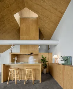 A modern minimalist kitchen with wooden features and a unique ceiling design.